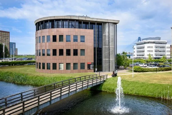 Modern kantoorgebouw aan het Rivium Quadrant met vijver, brug en fontein op de voorgrond.